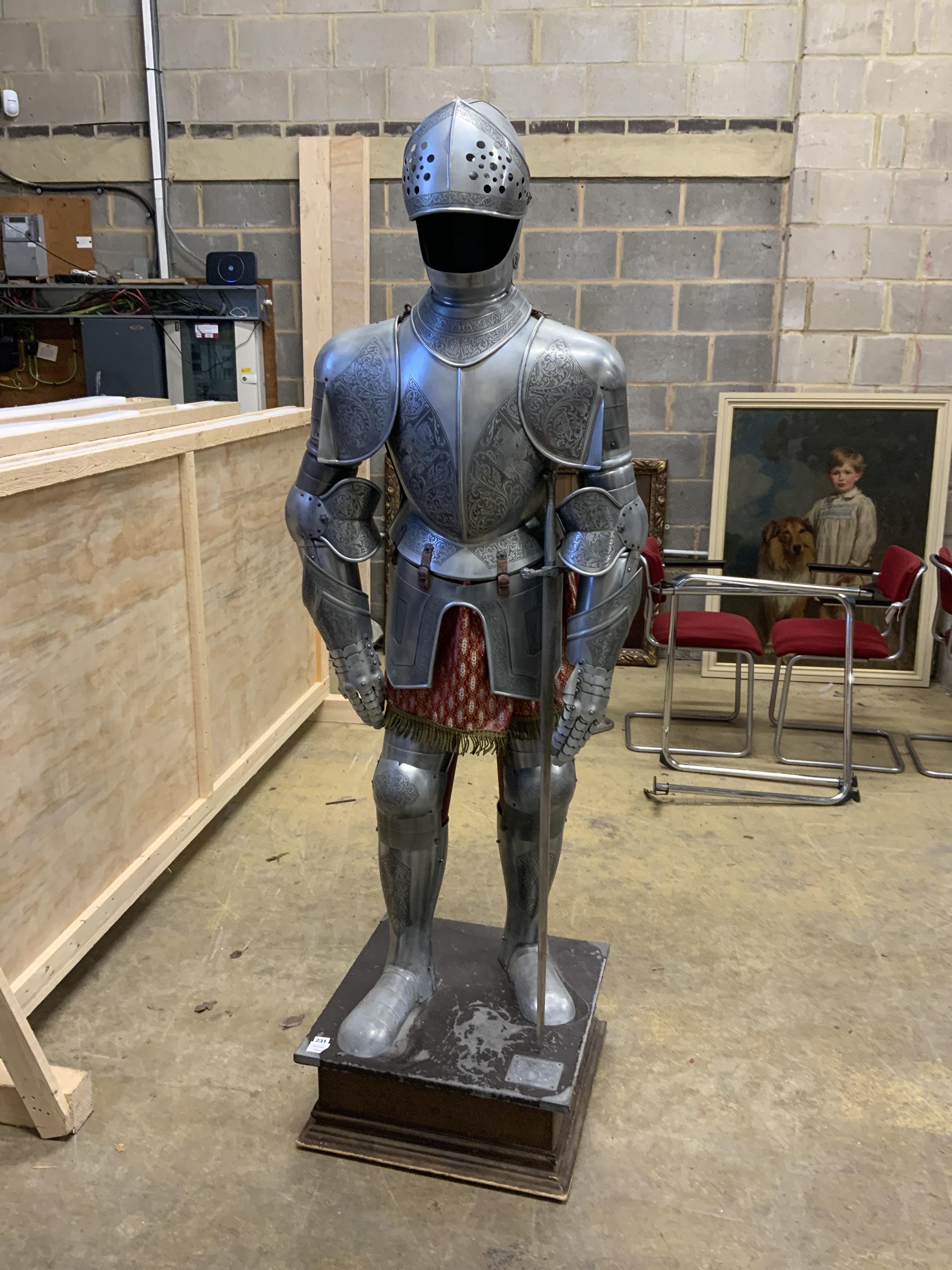 A full suit of reproduction armour produced in Spain by Marto, etch engraved decoration and including a broadsword, mounted on a display plinth and stand with applied makers label
